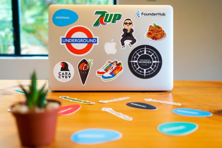 Laptop covered with colorful stickers on wooden desk